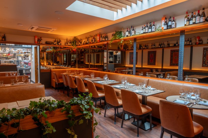 Salumeria Rosi dining room with brown leather seating, mirrors and wine shelves.
