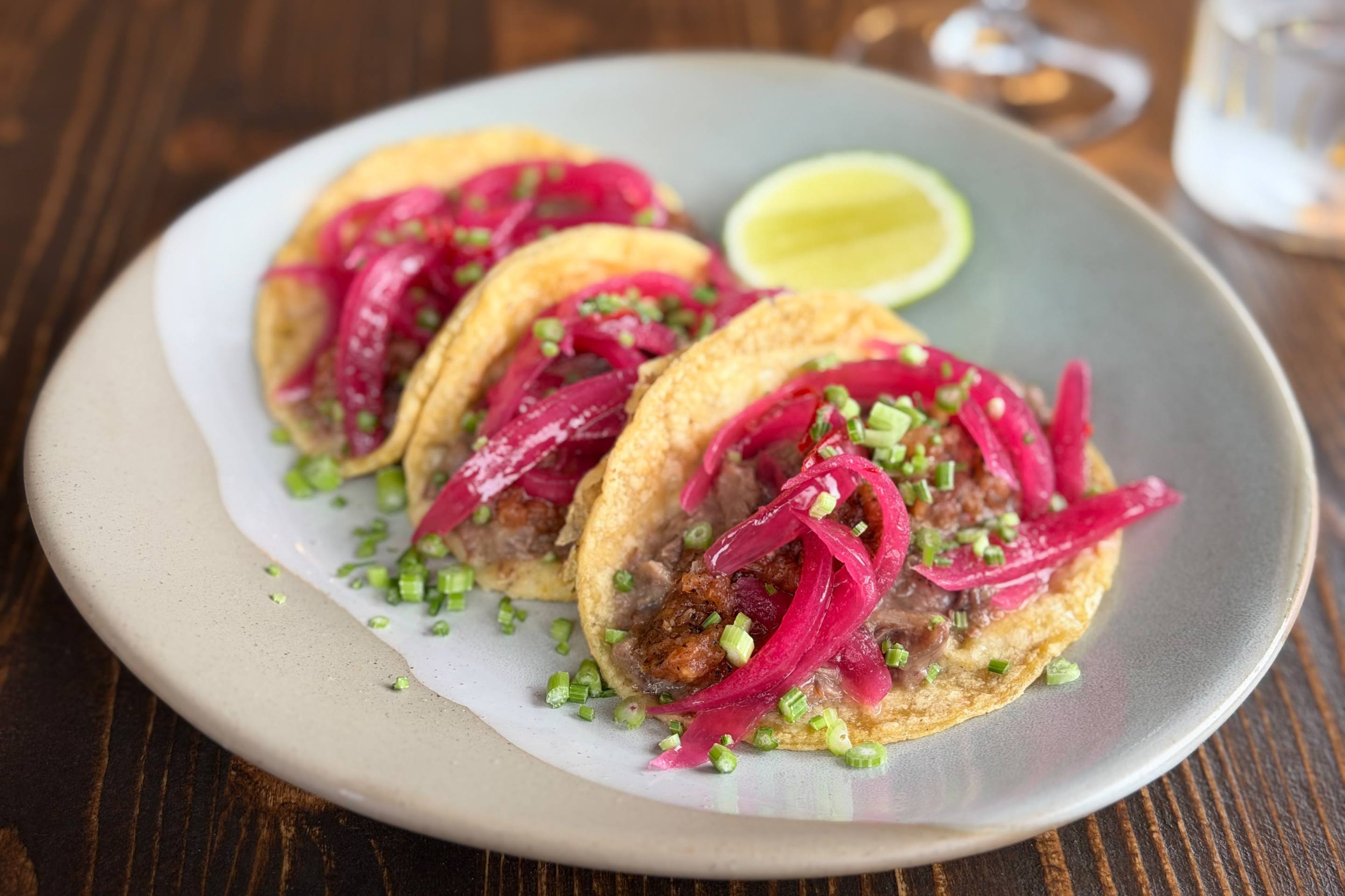 Three beef tacos topped with red onion and chopped herbs at La Tana dell’Orso.