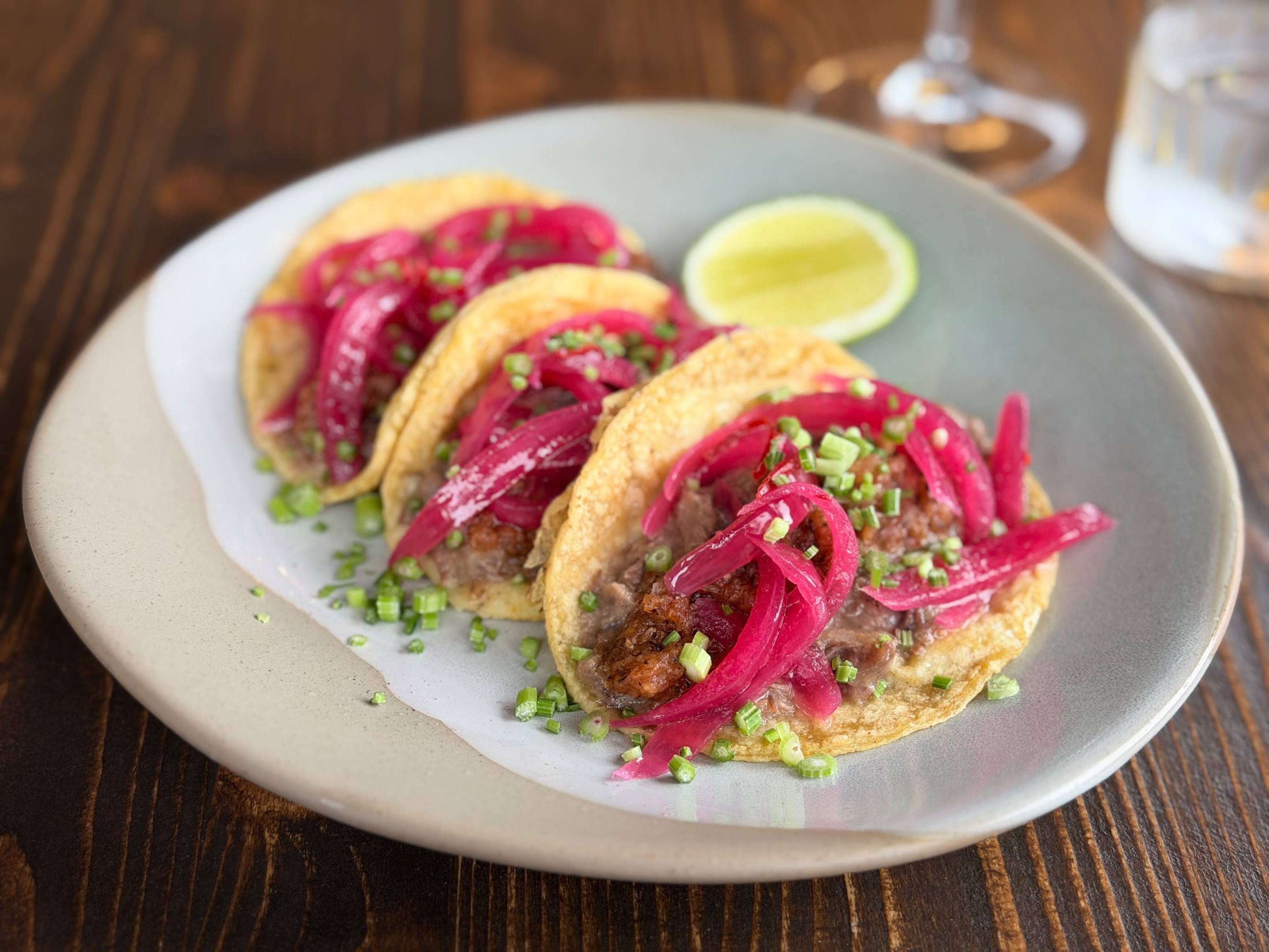 Three beef tacos topped with red onion and chopped herbs at La Tana dell’Orso.
