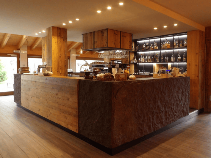 Wood-and-stone bar with illuminated bottle shelves at La Tana dell’Orso.