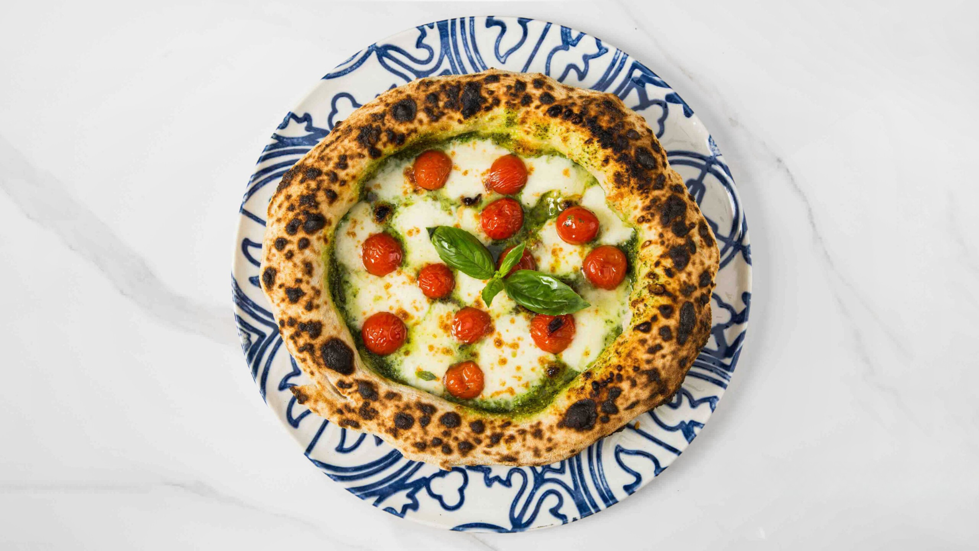 Audace’s Tricolore pizza with tomatoes, melted cheese and basil on a patterned plate.
